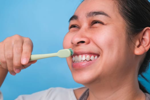 Happy Asian woman taking care of her teeth and holding a toothbrush. Young lady brushing her teeth. dental care and oral hygiene concept.