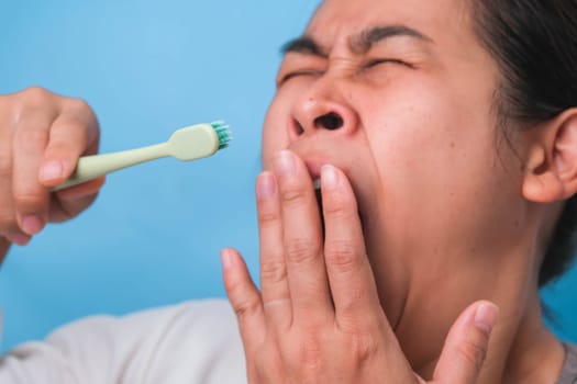 Yawn woman wake up with tooth brush on blue background. Oral care concept.