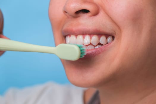 Happy Asian woman taking care of her teeth and holding a toothbrush. Young lady brushing her teeth. dental care and oral hygiene concept.