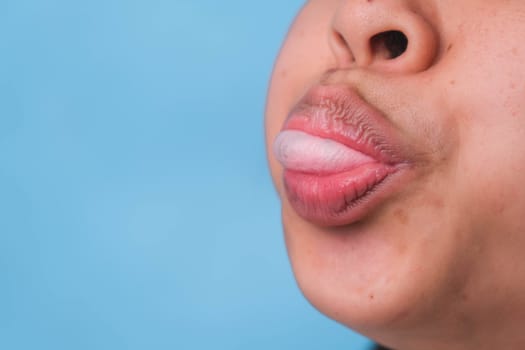 Young woman chewing gum and blowing bubble gum on blue background.