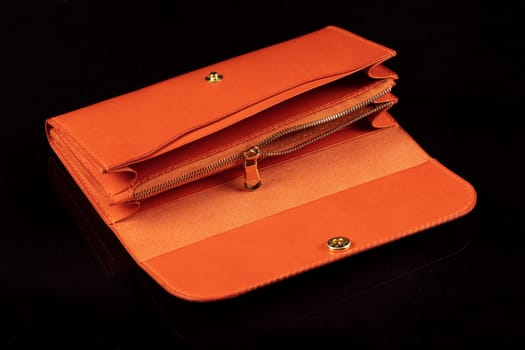 Orange leather open wallet on a dark background.