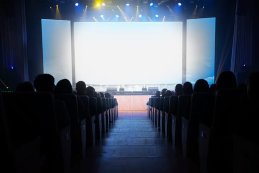 People in the cinema in front of an empty white screen.