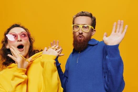 Man and woman couple smiling cheerfully and crooked with glasses, on yellow background, symbols signs and hand gestures, family shoot, newlyweds. High quality photo