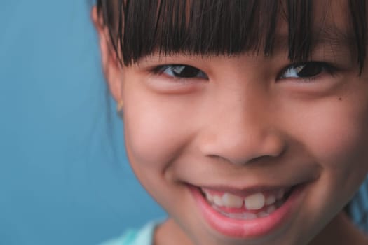 Close-up of smiling young girl revealing her beautiful white teeth on a blue background. Concept of good health in childhood.