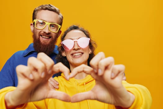 Man and woman couple smiling cheerfully and crooked with glasses, on yellow background, symbols signs and hand gestures, family shoot, newlyweds. High quality photo