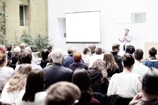 Speaker Giving a Talk at Business Meeting. Audience in the conference hall. Business and Entrepreneurship. Copy space on white board.