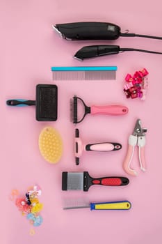 Tool for the groomer on a pink background. Dog grooming accessories. Combs and brushes for animals. View from above