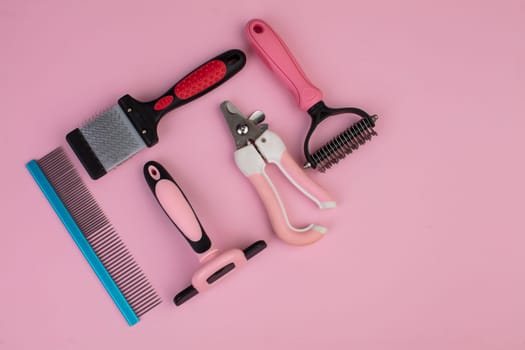 Tool for the groomer on a pink background. Dog grooming accessories. Combs and brushes for animals. View from above