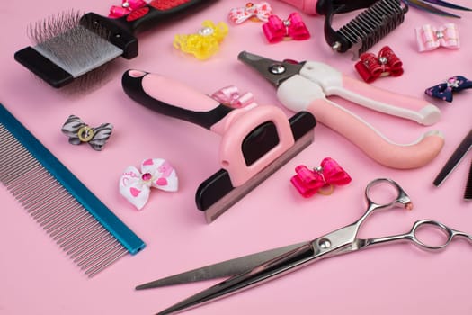 Tool for the groomer on a pink background. Dog grooming accessories. Combs and brushes for animals. View from above