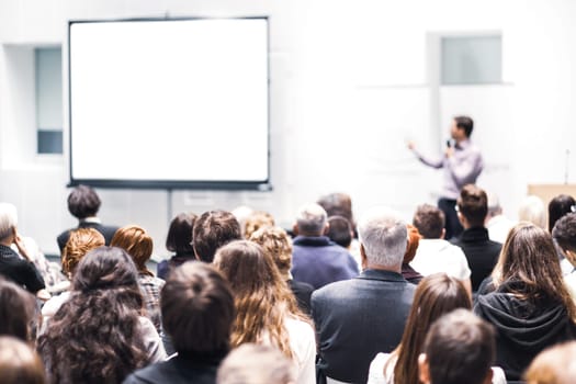 Speaker Giving a Talk at Business Meeting. Audience in the conference hall. Business and Entrepreneurship. Copy space on white board.