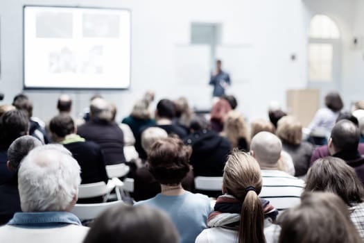 Speaker Giving a Talk at Business Meeting. Audience in the conference hall. Business and Entrepreneurship. Copy space on white board.