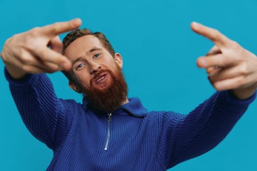 Portrait of a man in a sweater smile and happiness, hand signs and symbols, on a blue background. Lifestyle positive, copy place. High quality photo