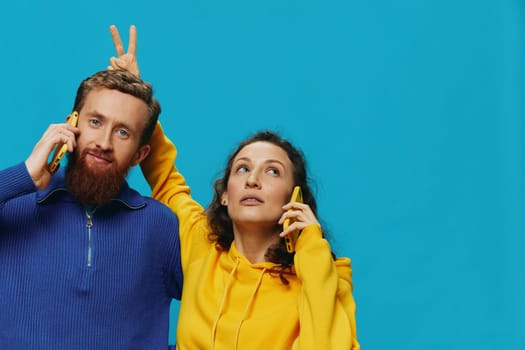 Woman and man cheerful couple with phones in their hands crooked smile cheerful, on blue background. The concept of real family relationships, talking on the phone, work online. High quality photo