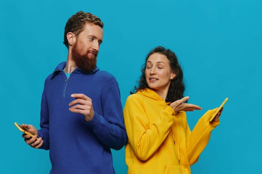 Woman and man cheerful couple with phones in their hands crooked smile cheerful, on blue background. The concept of real family relationships, talking on the phone, work online. High quality photo