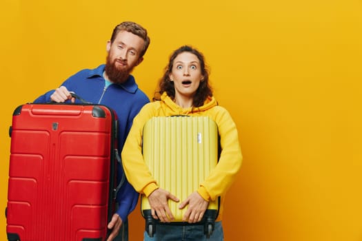 Woman and man smiling, suitcases in hand with yellow and red suitcase smiling merrily and crooked, yellow background, going on a trip, family vacation trip, newlyweds. High quality photo