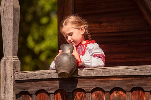 Girl in Ukrainian national dress with a jug outdoors