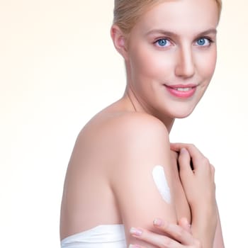 Closeup personable beautiful woman putting skincare moisturizer cream on her arm looking in camera in isolated background as concept for beauty care treatment. Female model applying lotion on her body