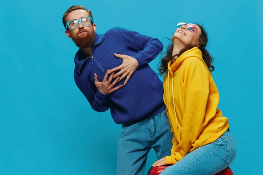 Woman and man smile sitting on suitcase with red suitcase smile, on blue background, packing for trip, family vacation trip. High quality photo