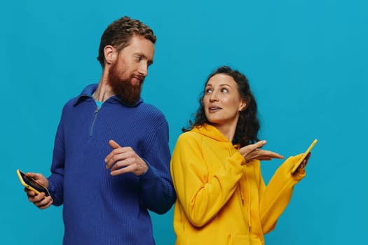 Woman and man cheerful couple with phones in their hands crooked smile cheerful, on blue background. The concept of real family relationships, talking on the phone, work online. High quality photo