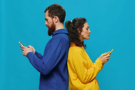 Woman and man cheerful couple with phones in their hands crooked smile cheerful, on blue background. The concept of real family relationships, talking on the phone, work online. High quality photo