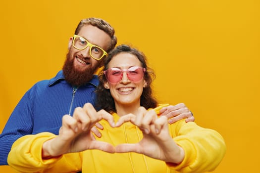 Man and woman couple smiling cheerfully and crooked with glasses, on yellow background, symbols signs and hand gestures, family shoot, newlyweds. High quality photo