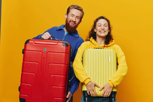 Woman and man smiling, suitcases in hand with yellow and red suitcase smiling merrily and crooked, yellow background, going on a trip, family vacation trip, newlyweds. High quality photo