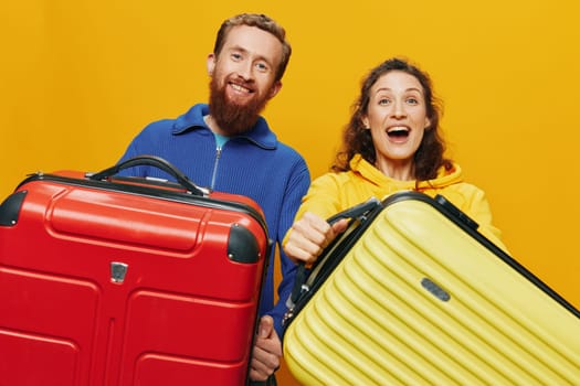 Woman and man smiling, suitcases in hand with yellow and red suitcase smiling merrily and crooked, yellow background, going on a trip, family vacation trip, newlyweds. High quality photo