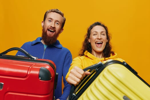 Woman and man smiling, suitcases in hand with yellow and red suitcase smiling merrily and crooked, yellow background, going on a trip, family vacation trip, newlyweds. High quality photo