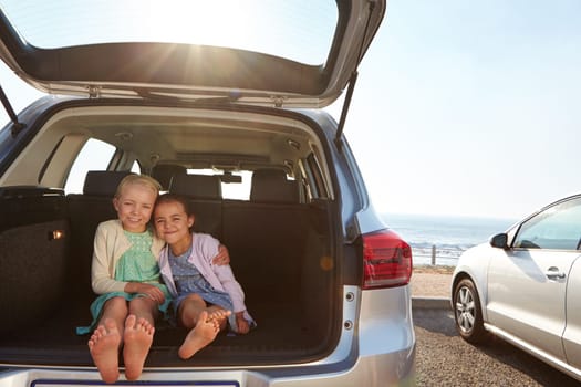 Travel buddies. two little girls sitting in the trunk of a car