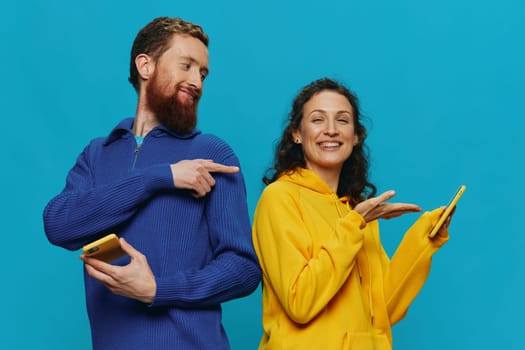 Woman and man cheerful couple with phones in their hands crooked smile cheerful, on blue background. The concept of real family relationships, talking on the phone, work online. High quality photo