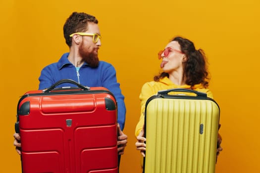 Woman and man smiling, suitcases in hand with yellow and red suitcase smiling merrily and crooked, yellow background, going on a trip, family vacation trip, newlyweds. High quality photo