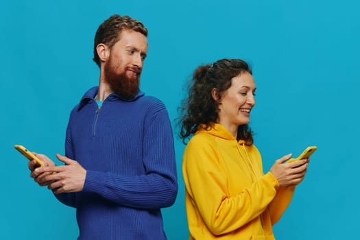 Woman and man cheerful couple with phones in their hands crooked smile cheerful, on blue background. The concept of real family relationships, talking on the phone, work online. High quality photo