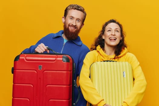 Woman and man smiling, suitcases in hand with yellow and red suitcase smiling merrily and crooked, yellow background, going on a trip, family vacation trip, newlyweds. High quality photo