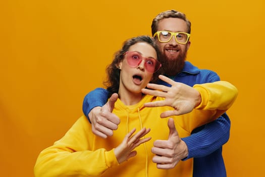 Man and woman couple smiling cheerfully and crooked with glasses, on yellow background, symbols signs and hand gestures, family shoot, newlyweds. High quality photo