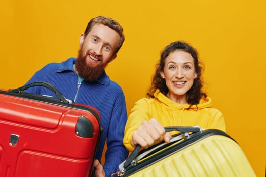 Woman and man smiling, suitcases in hand with yellow and red suitcase smiling merrily and crooked, yellow background, going on a trip, family vacation trip, newlyweds. High quality photo