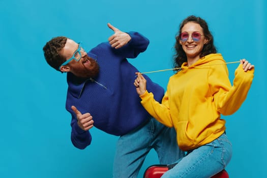 Woman and man smile sitting on suitcase with red suitcase smile, on blue background, packing for trip, family vacation trip. High quality photo