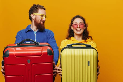 Woman and man smiling, suitcases in hand with yellow and red suitcase smiling merrily and crooked, yellow background, going on a trip, family vacation trip, newlyweds. High quality photo