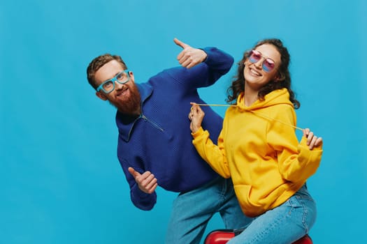 Woman and man smile sitting on suitcase with red suitcase smile, on blue background, packing for trip, family vacation trip. High quality photo