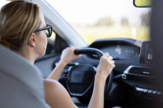 Business woman driving a car to work. Female driver steering car on the road.