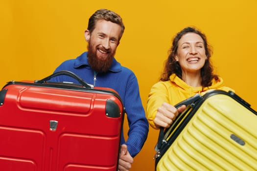 Woman and man smiling, suitcases in hand with yellow and red suitcase smiling merrily and crooked, yellow background, going on a trip, family vacation trip, newlyweds. High quality photo