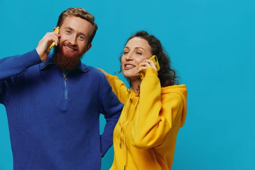 Woman and man cheerful couple with phones in their hands crooked smile cheerful, on blue background. The concept of real family relationships, talking on the phone, work online. High quality photo