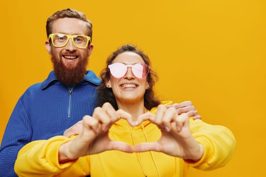 Man and woman couple smiling cheerfully and crooked with glasses, on yellow background, symbols signs and hand gestures, family shoot, newlyweds. High quality photo