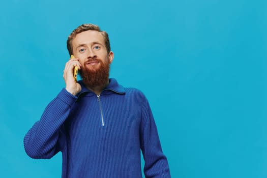 Portrait of man redheaded man with beard in sweater smile and happiness, hand signs and symbols, on blue background. Lifestyle positive, copy place. High quality photo