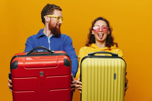 Woman and man smiling, suitcases in hand with yellow and red suitcase smiling merrily and crooked, yellow background, going on a trip, family vacation trip, newlyweds. High quality photo