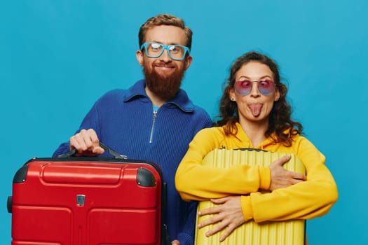 Woman and man smile suitcases in hand with yellow and red suitcase smile fun, on blue background, packing for a trip, family vacation trip. High quality photo