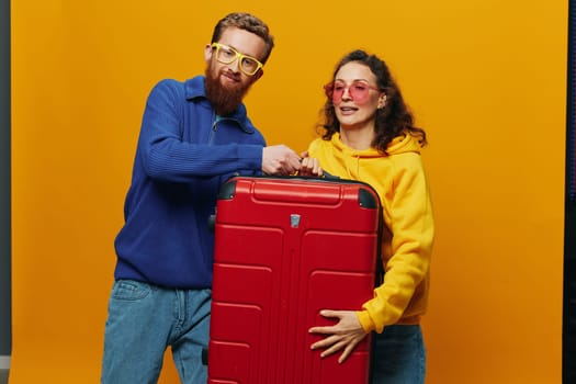 Woman and man smiling, suitcases in hand with yellow and red suitcase smiling merrily and crooked, yellow background, going on a trip, family vacation trip, newlyweds. High quality photo