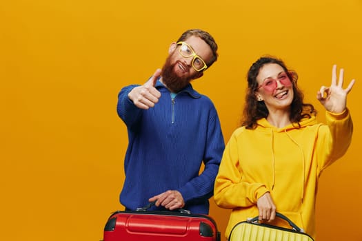 Woman and man smiling, suitcases in hand with yellow and red suitcase smiling merrily and crooked, yellow background, going on a trip, family vacation trip, newlyweds. High quality photo