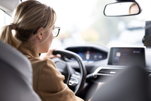 Business woman driving a car to work. Female driver steering car on the road.