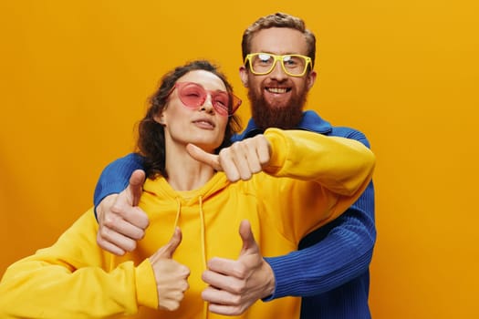 Man and woman couple smiling cheerfully and crooked with glasses, on yellow background, symbols signs and hand gestures, family shoot, newlyweds. High quality photo