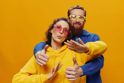 Man and woman couple smiling cheerfully and crooked with glasses, on yellow background, symbols signs and hand gestures, family shoot, newlyweds. High quality photo